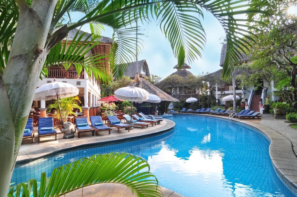 a swimming pool at a resort with chairs and umbrellas at Sativa Sanur Cottages in Sanur