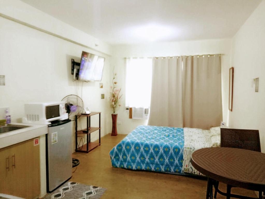 ein Schlafzimmer mit einem Bett und eine Küche mit einem Tisch in der Unterkunft San Remo Oasis Cebu- Vic Place in Cebu City