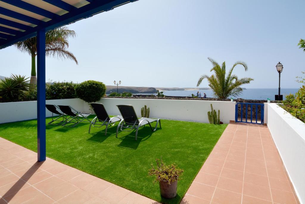 um pátio com cadeiras e um relvado com o oceano ao fundo em Villa Vista Mar em Playa Blanca