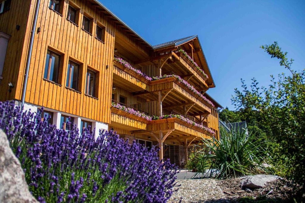 un bâtiment en bois avec des fleurs violettes devant lui dans l'établissement Les Gîtes d'Adelspach Gîtes & Spa en Alsace, à Aubure