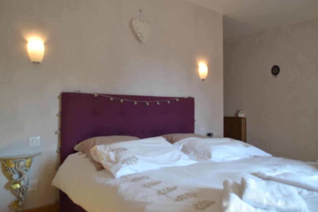 a bedroom with a bed with white sheets and pillows at La Ferme Pateli in Courouvre