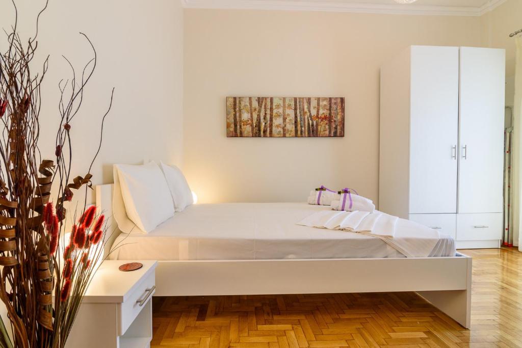 アテネにあるCharmy Petit Flat in Athensの白いベッドと壁に絵画が飾られたベッドルーム1室