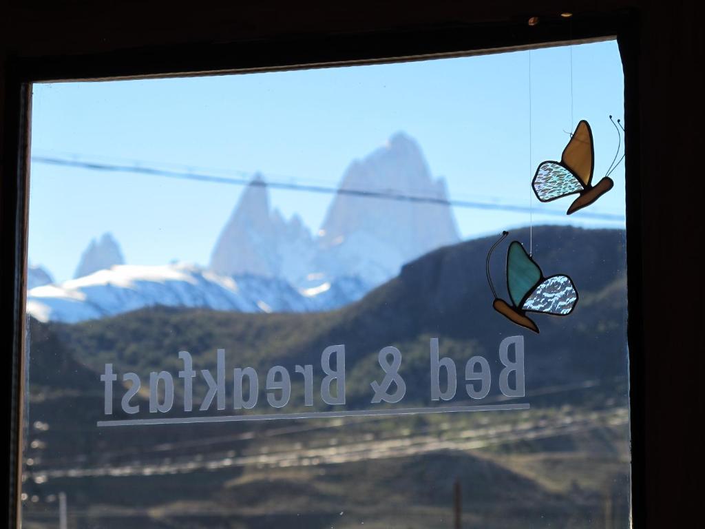 two butterflies on a window with mountains in the background at Patagonicus in El Chalten