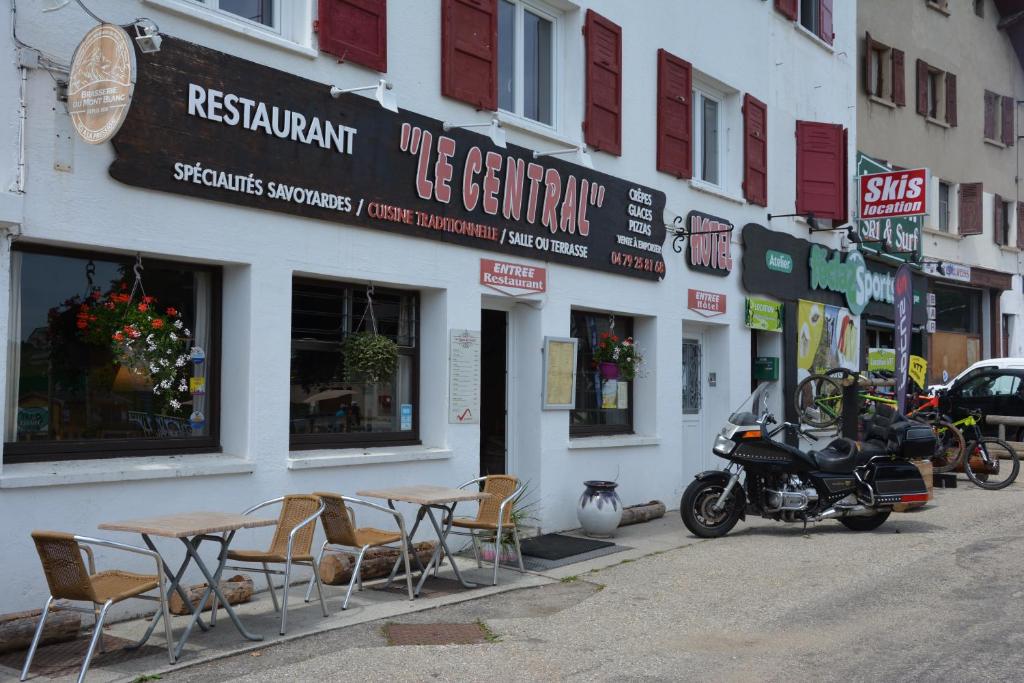a motorcycle parked in front of a restaurant with tables and chairs at Hotel Le Central in La Féclaz