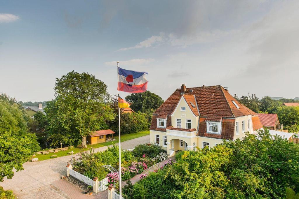 a house with a flag flying in front of it at Altes-Landhaus-Ferienwohnung-Schleswig-Holstein in Wendtorf