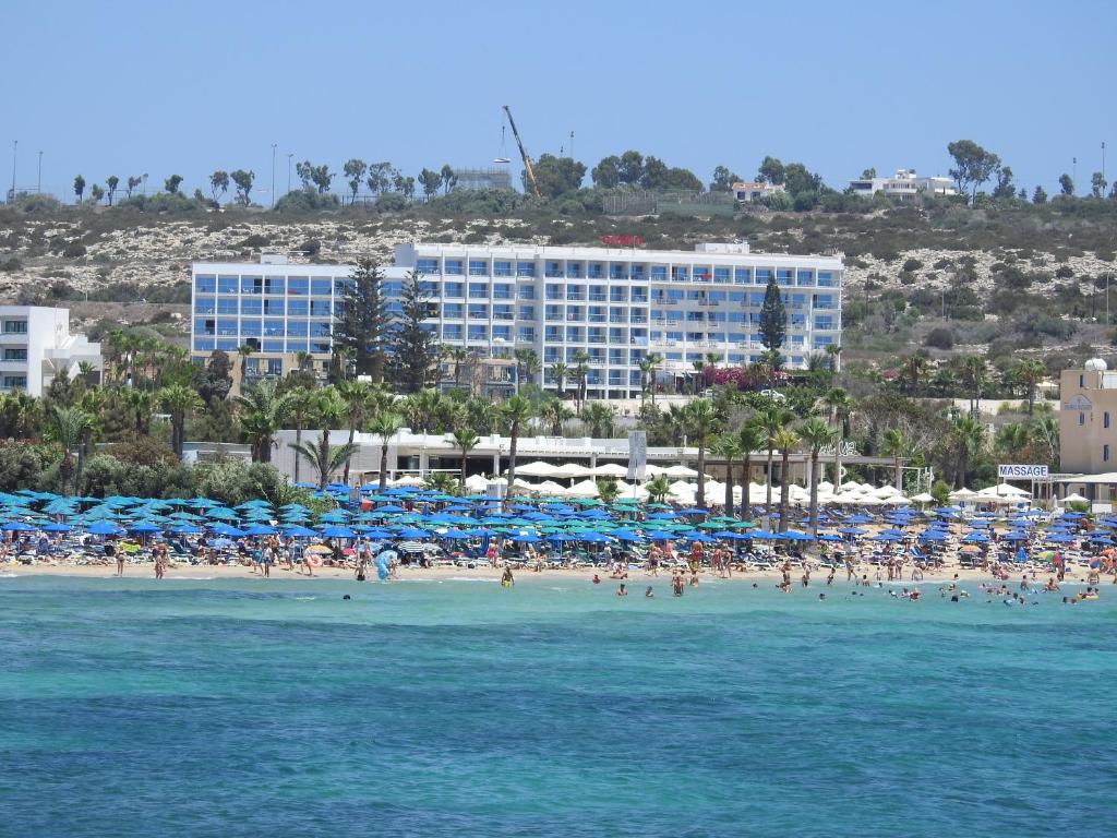 a group of people on a beach with umbrellas at Corfu Hotel in Ayia Napa