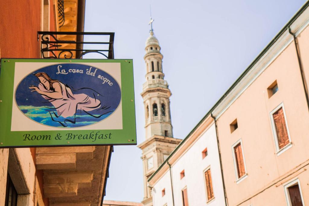 una señal en el lateral de un edificio con una torre de reloj en La Casa del Sogno, en Monteforte dʼAlpone