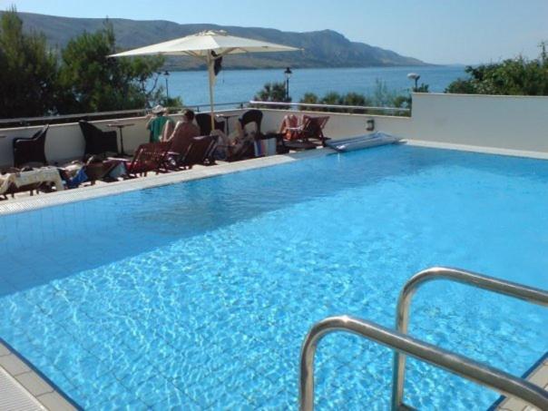 a large blue swimming pool with people sitting in chairs at Hotel Meridijan in Pag