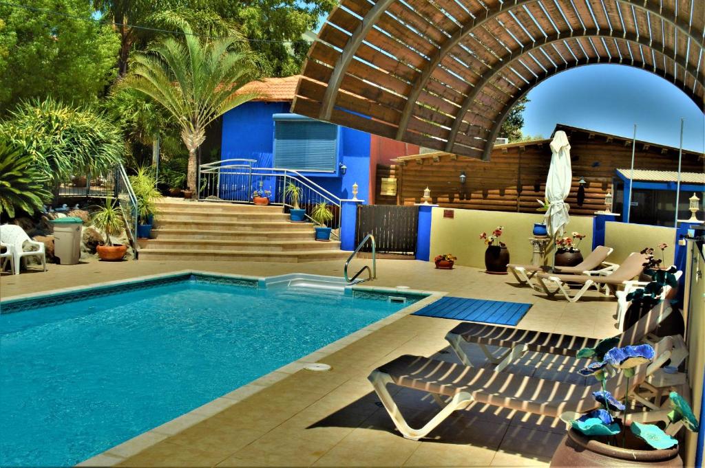 a swimming pool with chairs next to a house at Ayelet Ahavim in Livnim