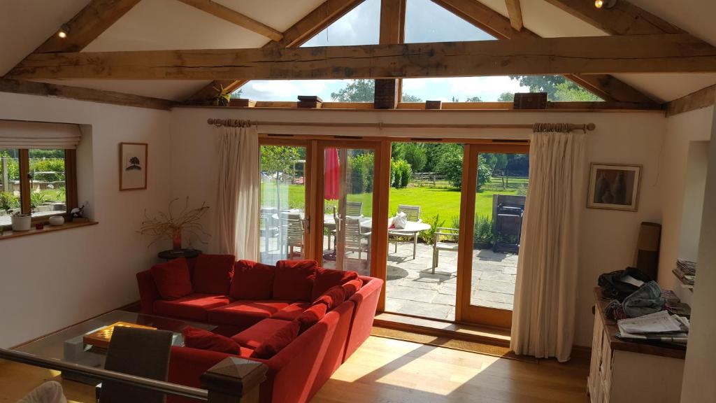 a living room with a red couch and sliding glass doors at Prestwick Oak in Haslemere