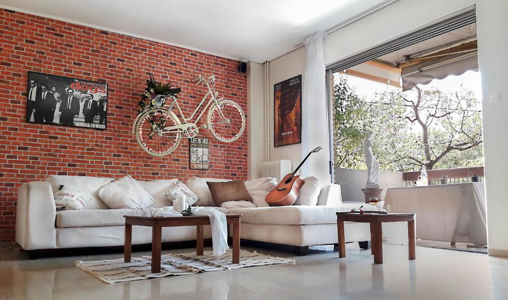 uma sala de estar com um sofá branco e uma parede de tijolos em Saki's apartment em Atenas