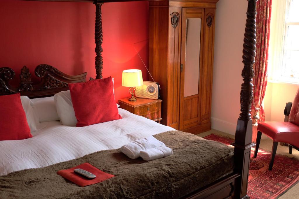 a bedroom with a large bed with red walls at The Old Court Hotel in Witney