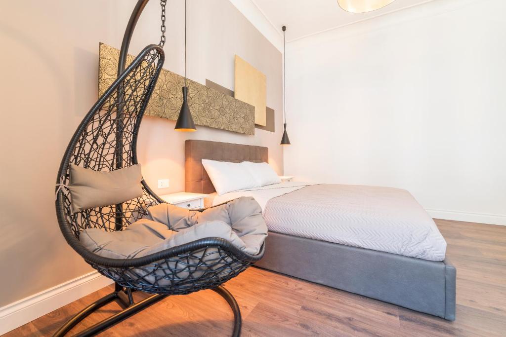 uma cadeira de baloiço de vime num quarto com uma cama em Guest Roma House em Roma