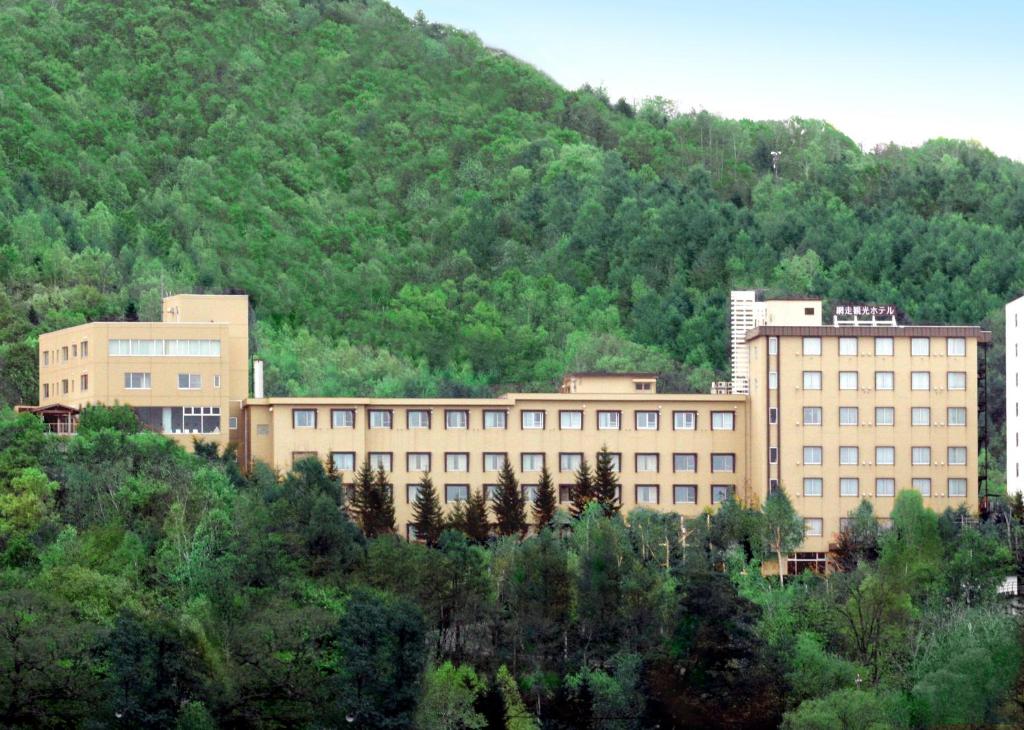 a group of buildings in front of a mountain at Abashiri Kanko Hotel in Abashiri