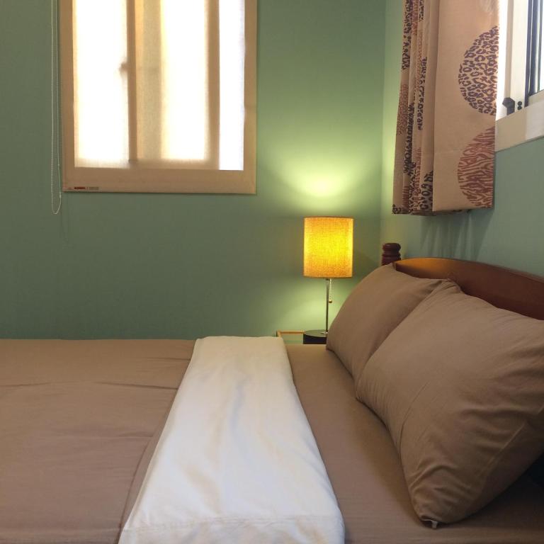 a bed in a room with a window and a lamp at Happy Tree Hostel in Jinning