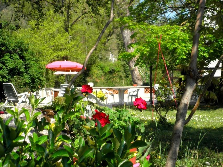 a garden with a table and an umbrella and flowers at La Pierre Lys in Quillan