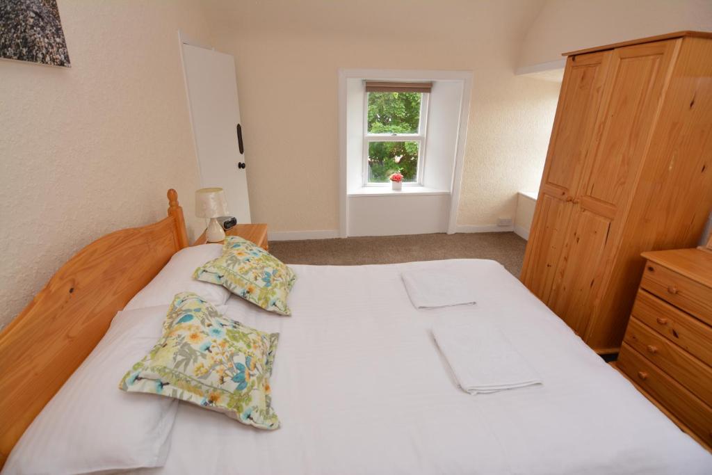 ein Schlafzimmer mit einem weißen Bett mit Kissen und einem Fenster in der Unterkunft Northness Apartments, Lerwick Self Contained in Lerwick