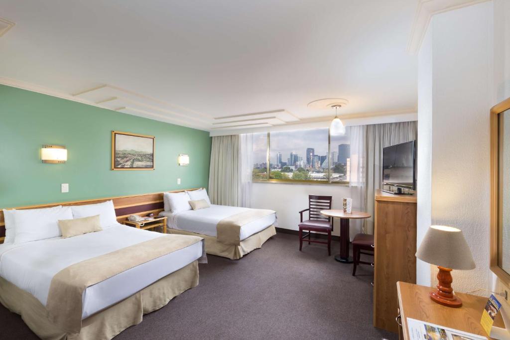 a hotel room with two beds and a table at Hotel Estoril in Mexico City