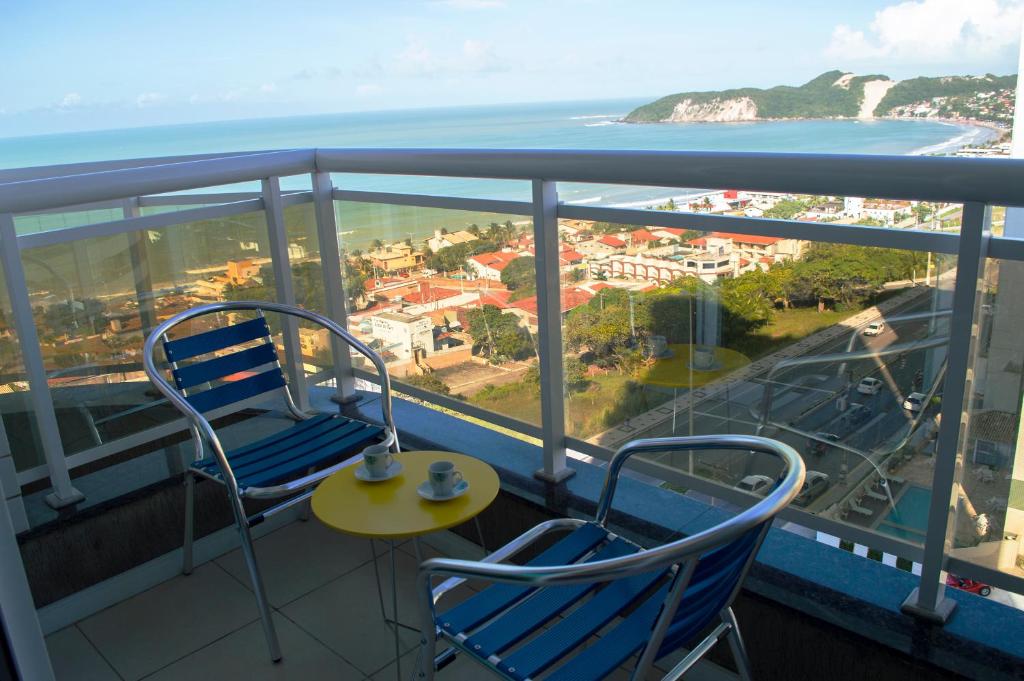 einen Balkon mit 2 Stühlen, einem Tisch und Meerblick in der Unterkunft Apartamento Deluxe Ahead Ponta Negra in Natal