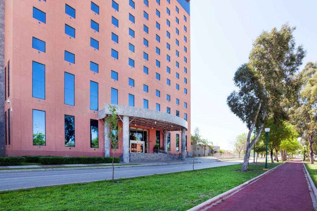 un grand bâtiment rose dans une rue à côté d'une route dans l'établissement Best Western PLUS Nuevo Laredo Inn & Suites, à Nuevo Laredo