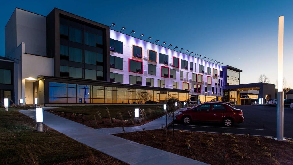 a red car parked in a parking lot in front of a building at Hotel Levesque in Rivi&egrave;re-du-Loup