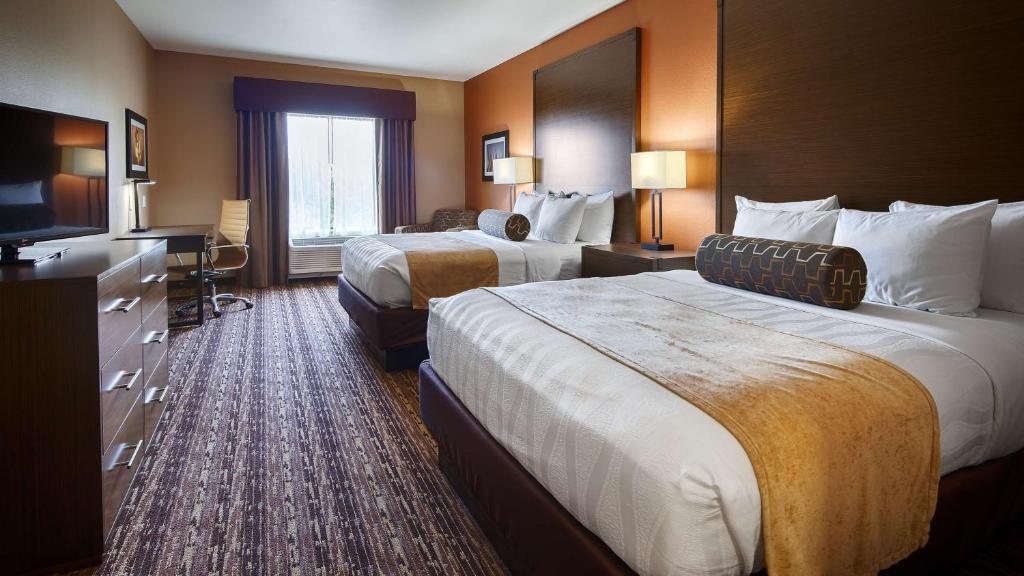 a hotel room with two beds and a flat screen tv at Best Western Plus Elmendorf Hotel San Antonio Hotel in Elmendorf