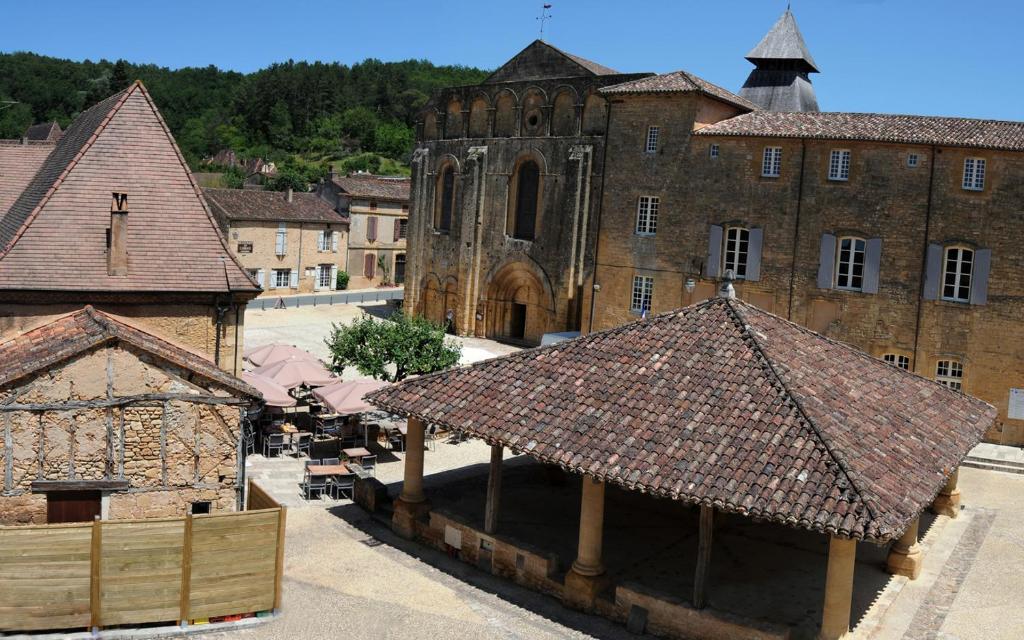 un antiguo edificio con una torre de reloj en una ciudad en Les Songes de l'Abbaye, en Cadouin