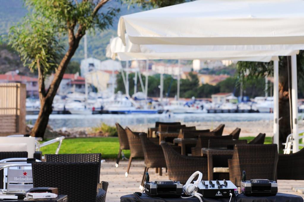 a group of tables and chairs with a marina in the background at Sporting Hotel Stella Maris in Bosa Marina