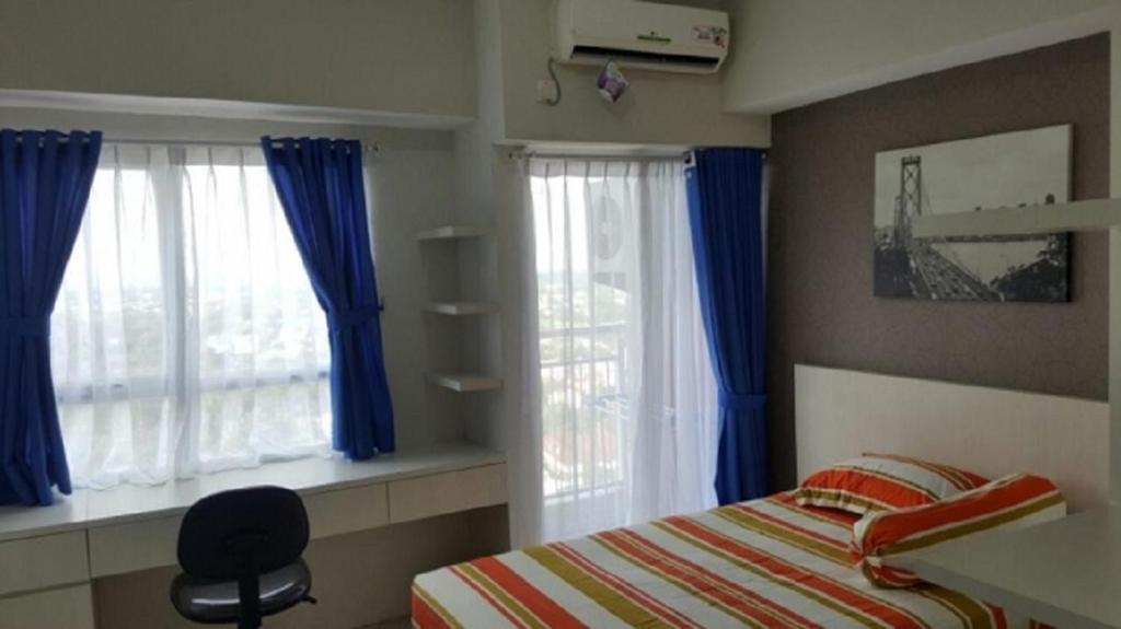 1 dormitorio con 1 cama y 2 ventanas con cortinas azules en DSR Apartment Margonda Residence 2, en Depok