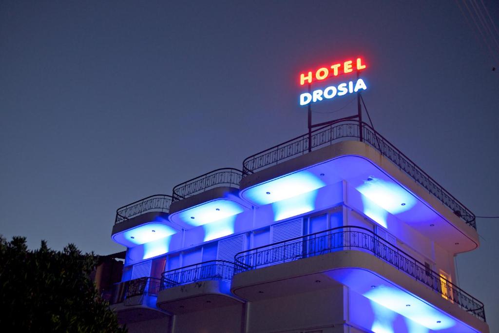 a hotel with a neon sign on top of it at Hotel Drosia in Messini