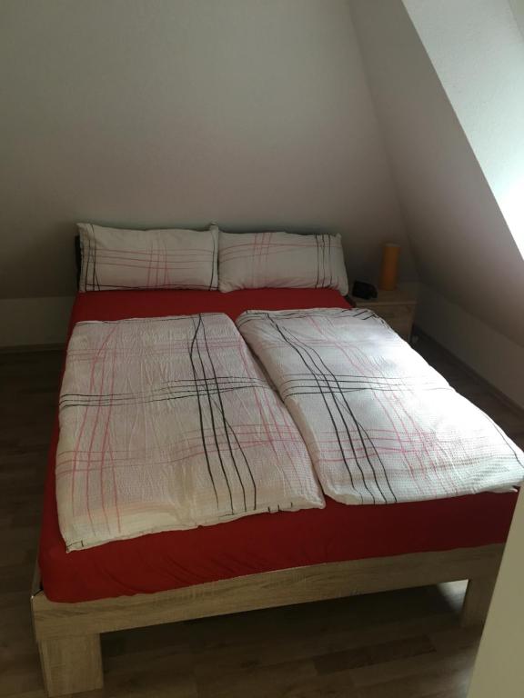 1 cama con almohadas y manta roja y blanca en Formella, en Eisenach