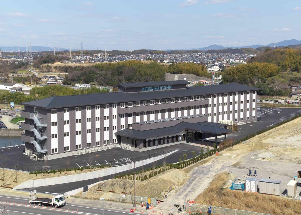 un gran edificio blanco con techo negro junto a una carretera en Hotel Route Inn Osaka Izumi -Kishiwada Izumi Inter-, en Izumi