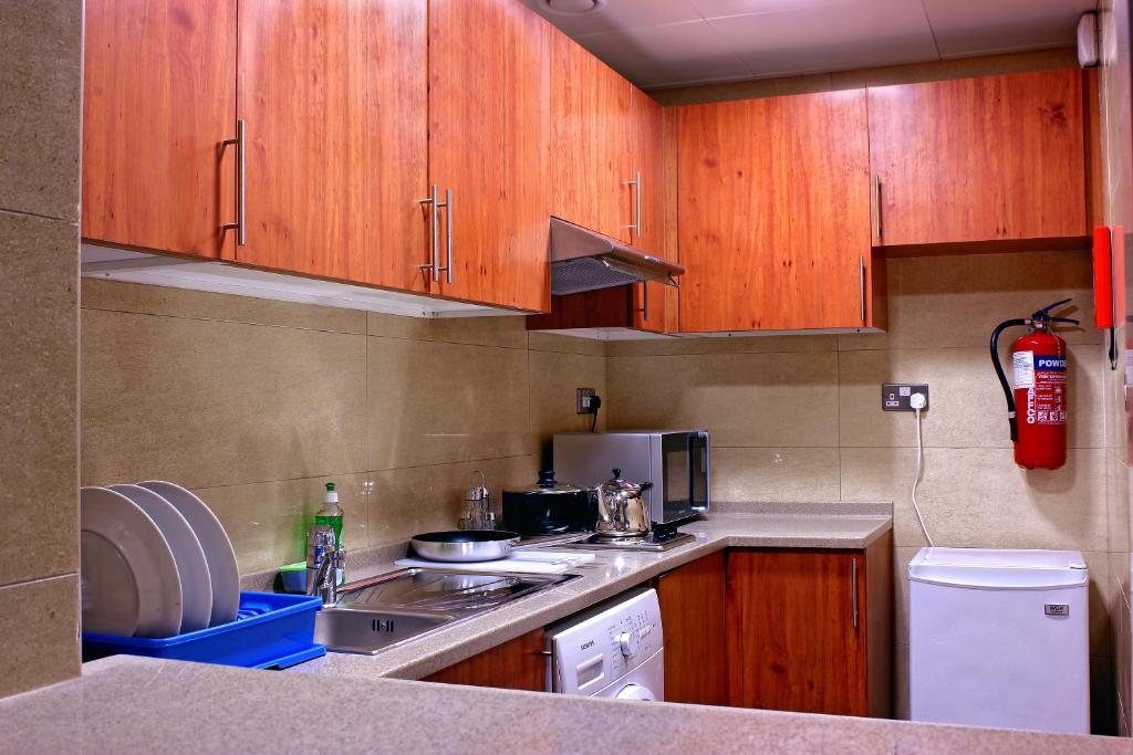 una pequeña cocina con armarios de madera y fregadero en Paragon Hotel Apartments, en Abu Dabi