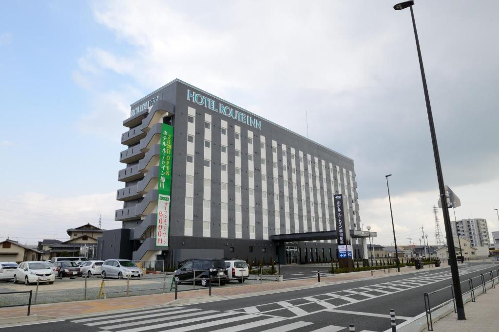 a large building with cars parked in a parking lot at Hotel Route-Inn Yanagawa Ekimae in Yanagawa