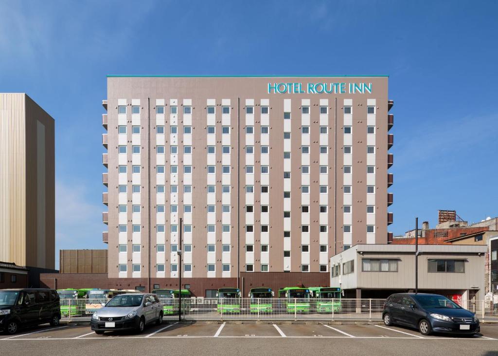 Hotel Route-Inn Takaoka Ekimae في تاكاوكا: نزل غرف الفندق مع سيارات تقف في موقف للسيارات