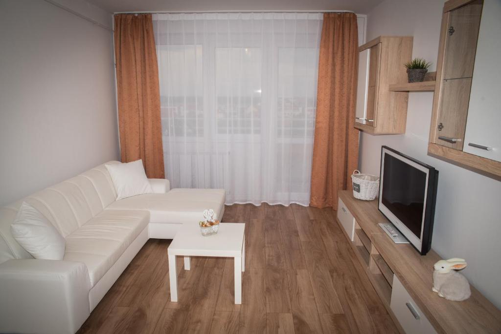 a living room with a white couch and a tv at Anna Apartman in Győr