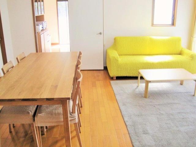 a living room with a table and a yellow couch at Kitchen Garden in Tateyama