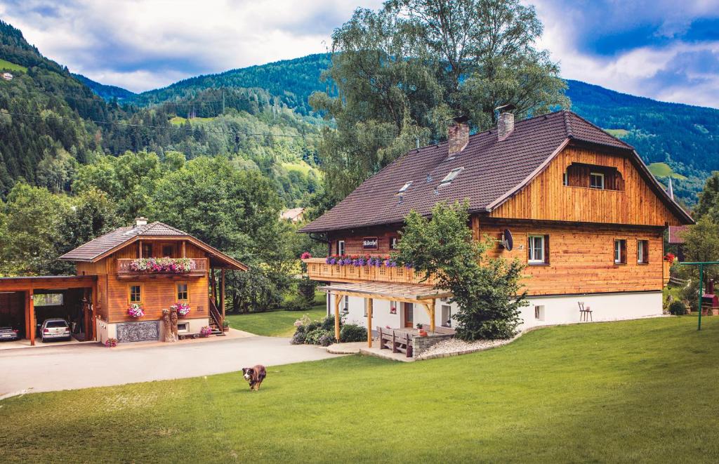 una gran casa de madera con un perro delante de ella en Raderhof, en Feld am See