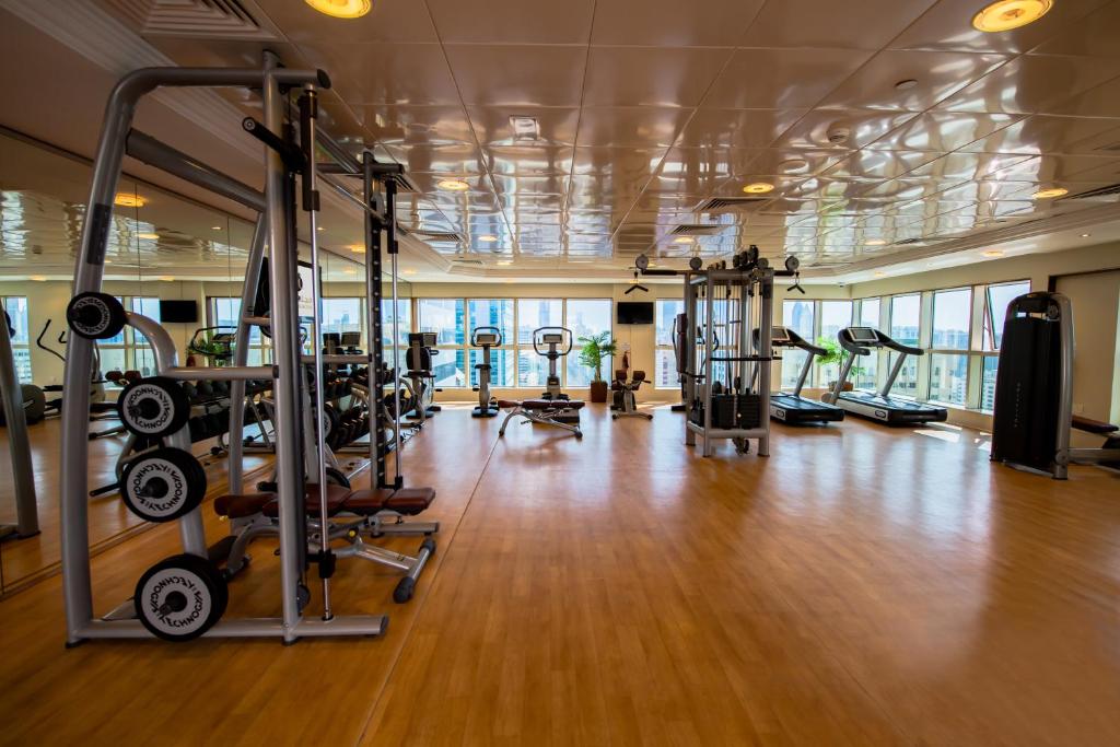 a gym with lots of treadmills and machines at Grand Mercure Majlis Residences in Abu Dhabi