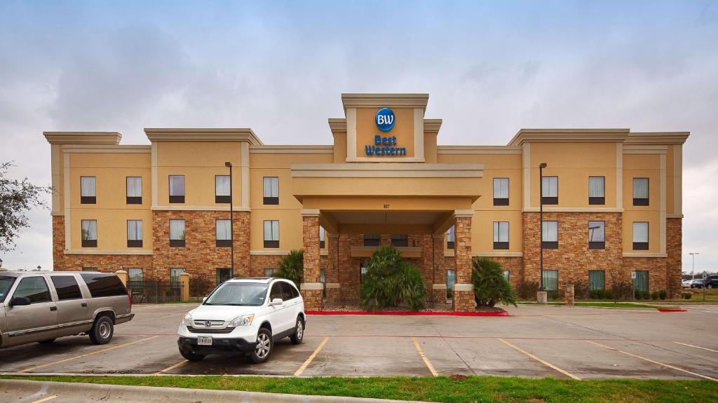 un coche aparcado en un aparcamiento frente a un edificio en Best Western Bastrop Pines Inn en Bastrop