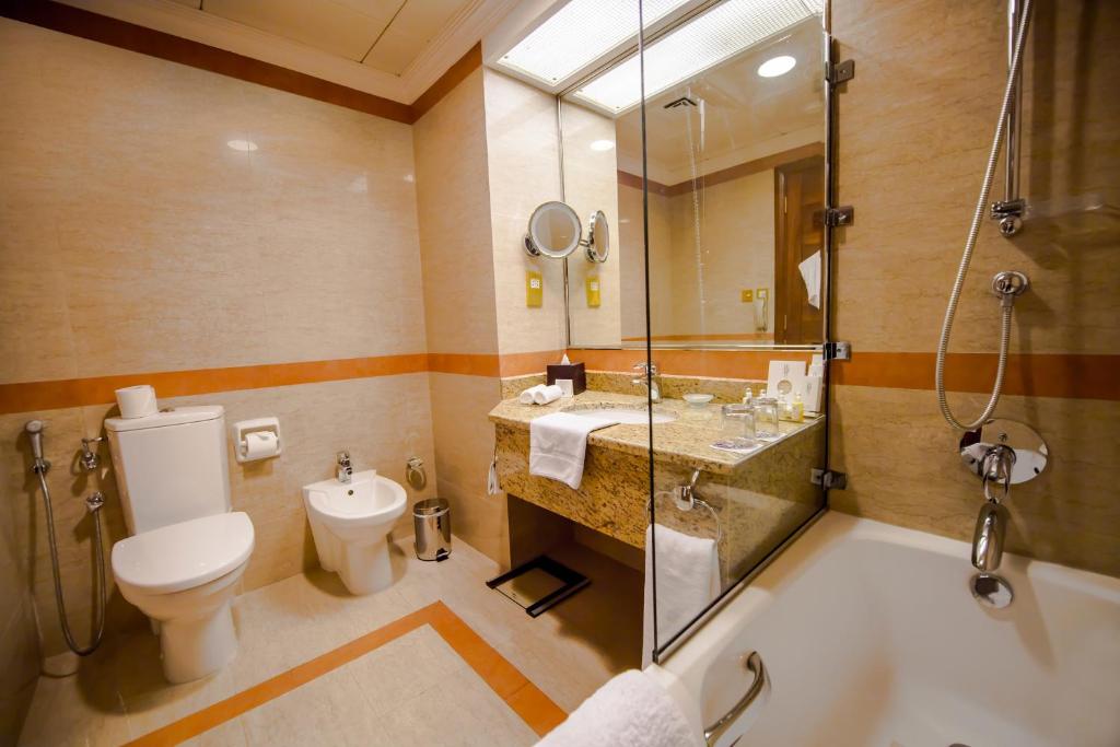 a bathroom with a toilet and a sink and a shower at Grand Mercure Majlis Residences in Abu Dhabi