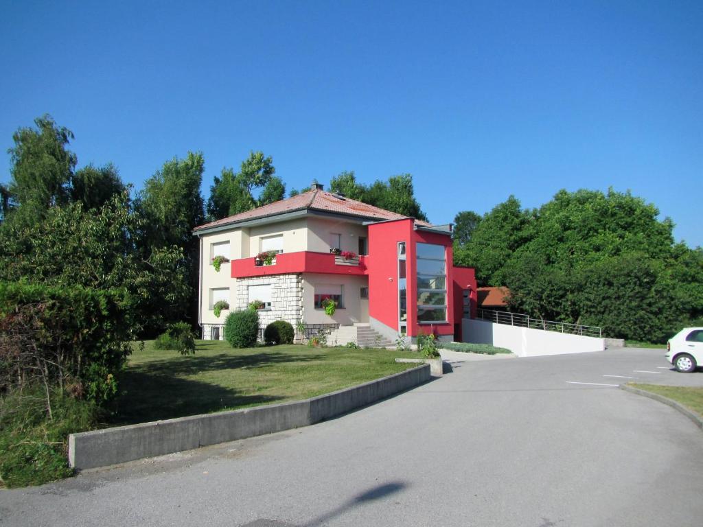 uma casa vermelha e branca na berma de uma estrada em Pod Orehi em Postojna
