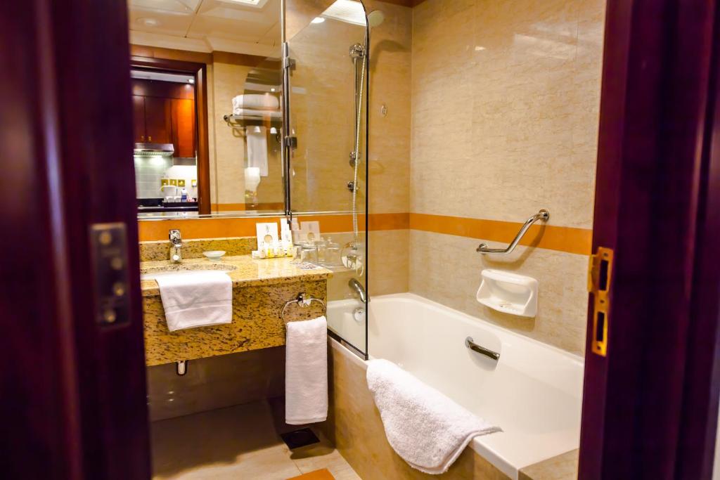 a bathroom with a tub and a sink and a shower at Grand Mercure Majlis Residences in Abu Dhabi