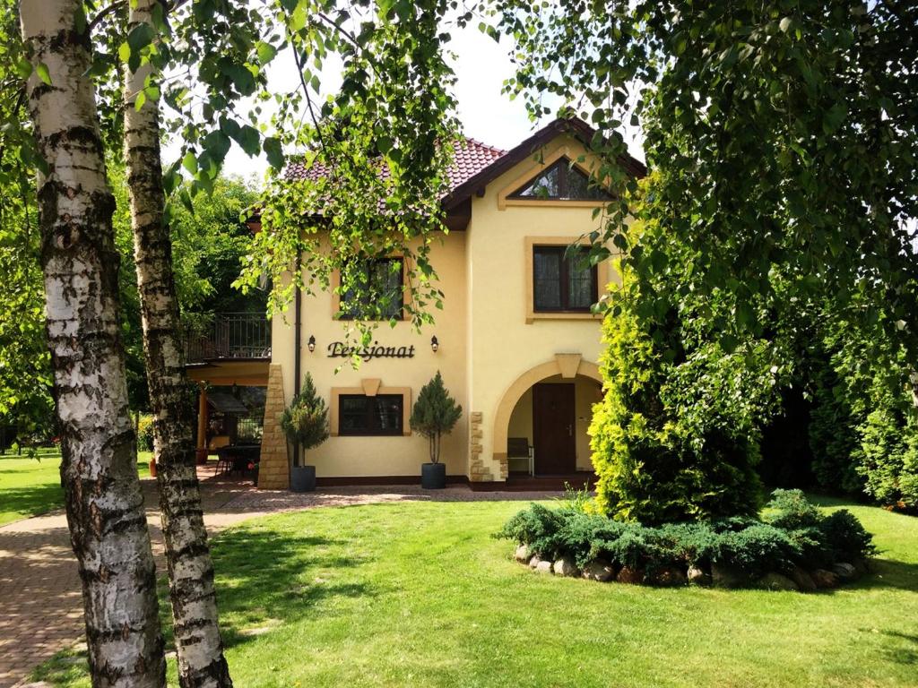 a house with trees in front of a yard at Pensjonat Pod Orzechami in Magdalenka