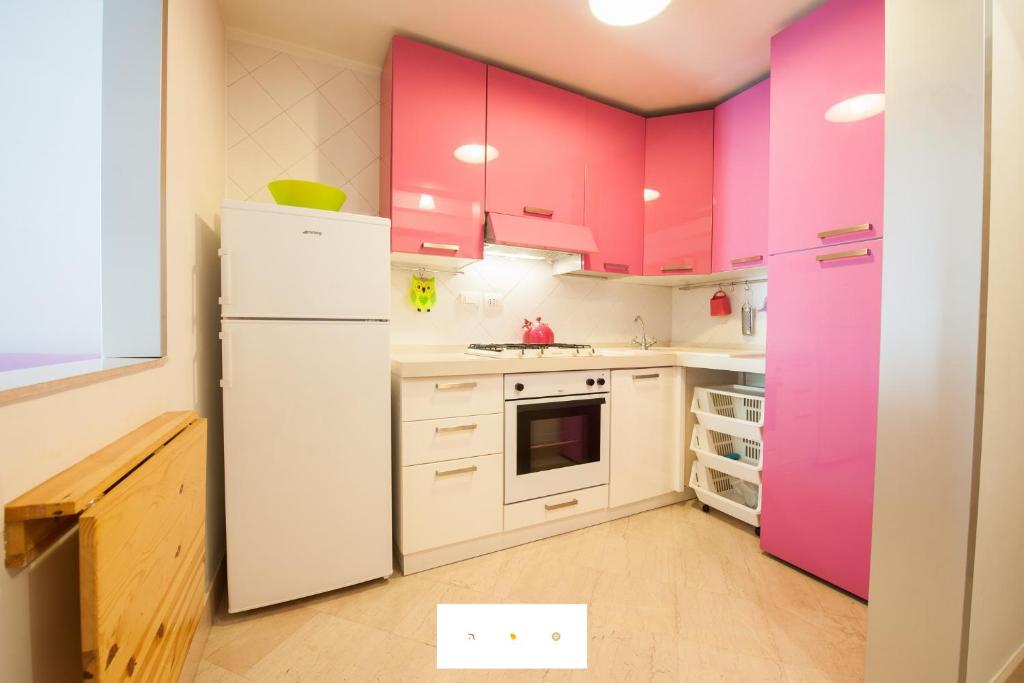 ナポリにあるLovely Holiday Apartmentのピンクのキャビネットと白い冷蔵庫付きのキッチンが備わります。