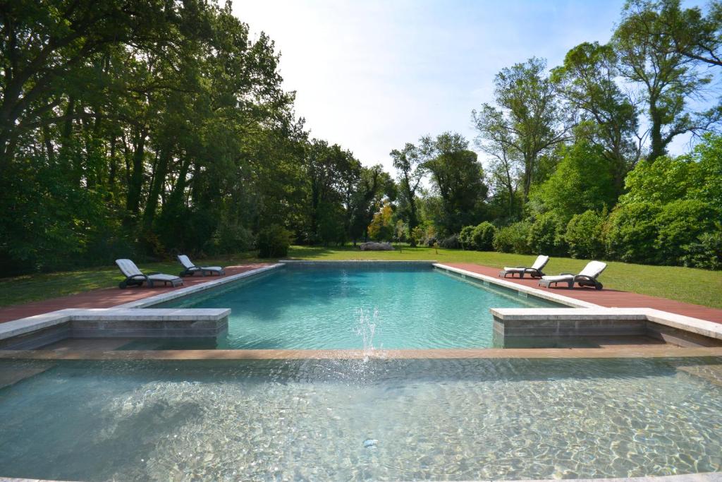 a swimming pool with two chairs and a fountain at Ancien Mas Du Moulin in Eygalières