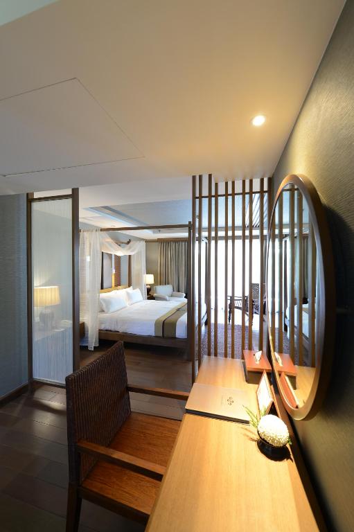 A compact wooden desk and chair positioned beside a guest bed.