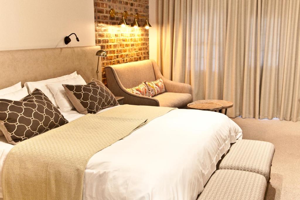a bedroom with a large bed and a chair at d'Olyfboom Guest House B & B in Paarl