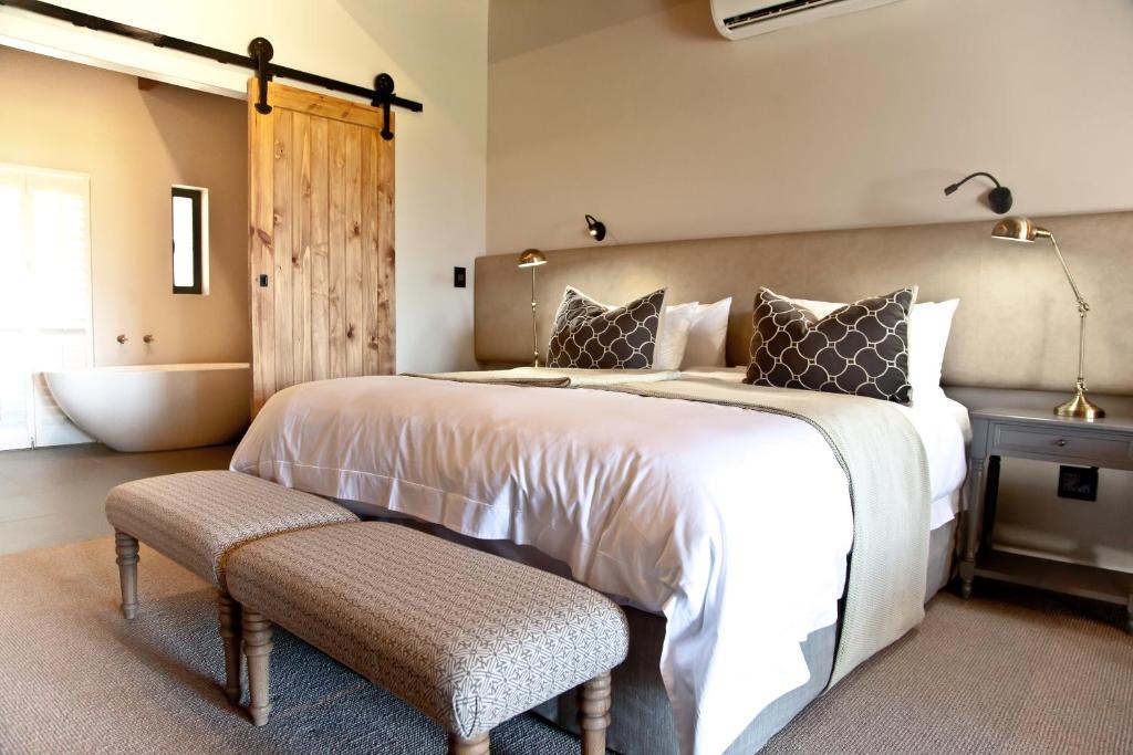 1 dormitorio con 1 cama grande y bañera en d'Olyfboom Guest House B & B en Paarl