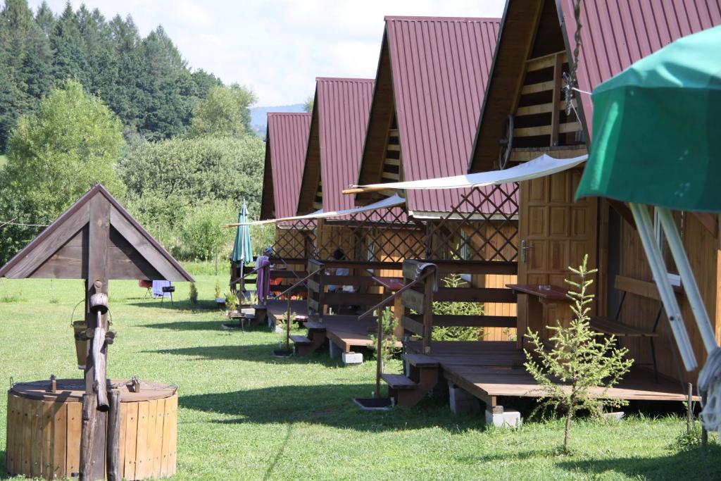 uma fila de alojamentos de turismo selvagem com bancos na relva em Domki Zacisze em Solina